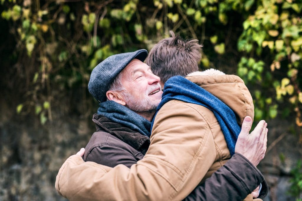 senior-father-and-his-young-son-on-a-walk-hugging-P3SZ5U3
