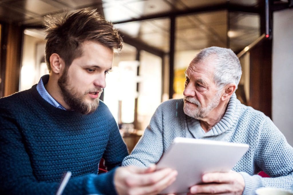 senior-father-and-young-son-with-tablet-in-a-cafe-PXL56G5